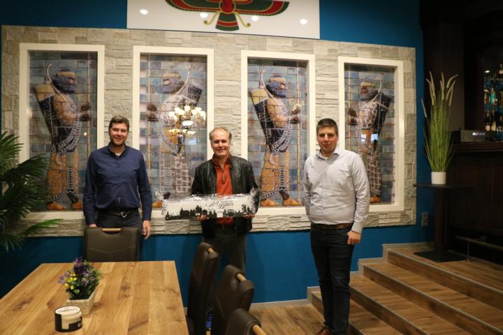 Frank Thole, Geschäftsführer der Tourist Information TIM e.V. (links) und Alexander Kassner, Wirtschaftsförderer der Stadt Meppen, gratulierten Gastronom Bahman Bayat (Mitte) und seinen Mitarbeitenden zur Neueröffnung und übergaben die „Meppener Skyline“. Foto: Stadt Meppen